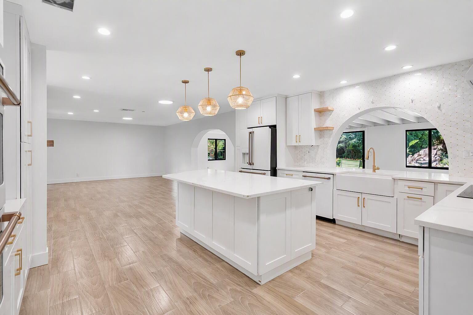 Kitchen at 10751 SW 25th Street in Davie, with a large white center island, wood-look floors, and pendant lights.